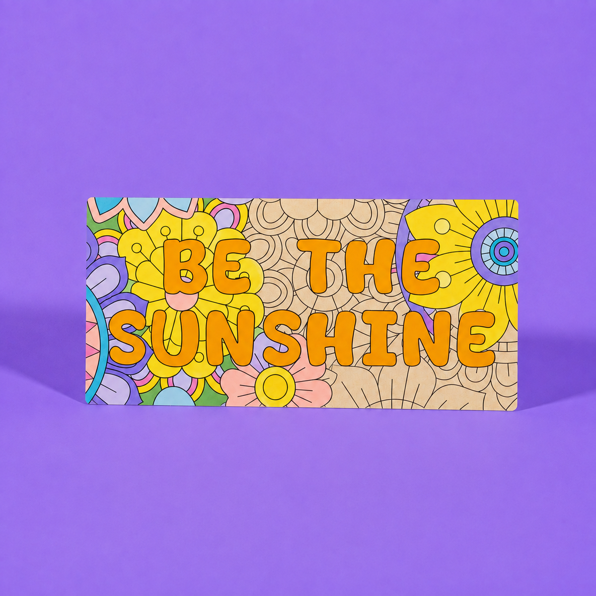 A rectangular art print with a colorful retro floral pattern and the text 'BE THE SUNSHINE' in orange bubble letters, displayed against a solid purple background.