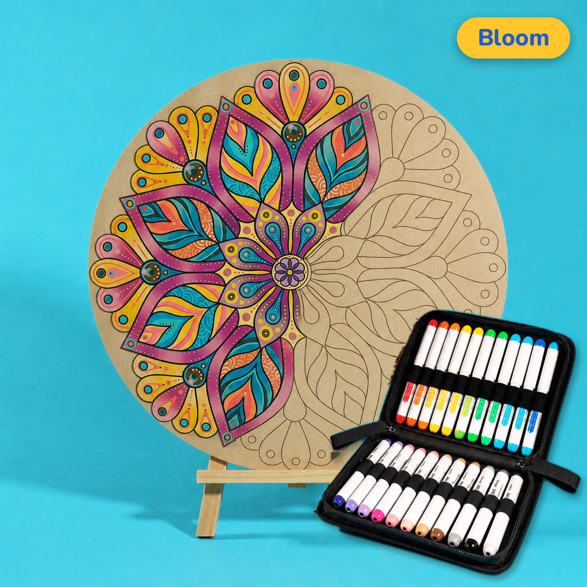 400mm Bloom engraved circle art board with mandala of layered leaves and petals, left half coloured magenta, teal and gold, beside a case of 24 Nahuku markers