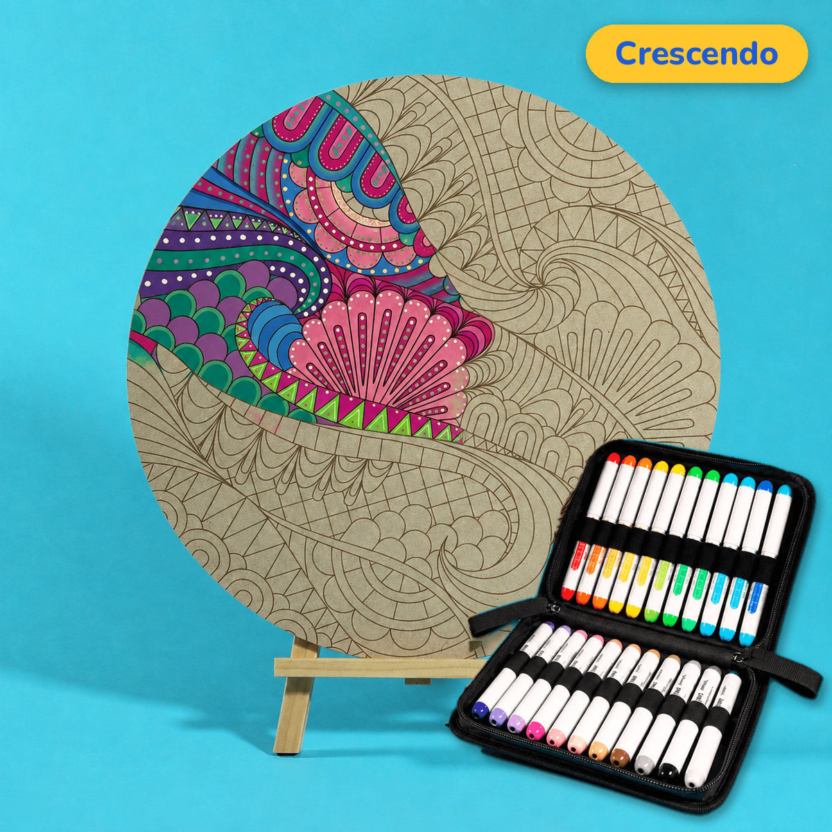400mm Crescendo engraved circle art board with shells and flowing wave lines, upper left coloured pink, purple and teal, beside a case of 24 Nahuku markers