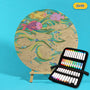 400mm Drift engraved circle art board with fish, flowing waves and bubbles, top coloured with pink fish and green waves, beside a case of 24 Nahuku markers