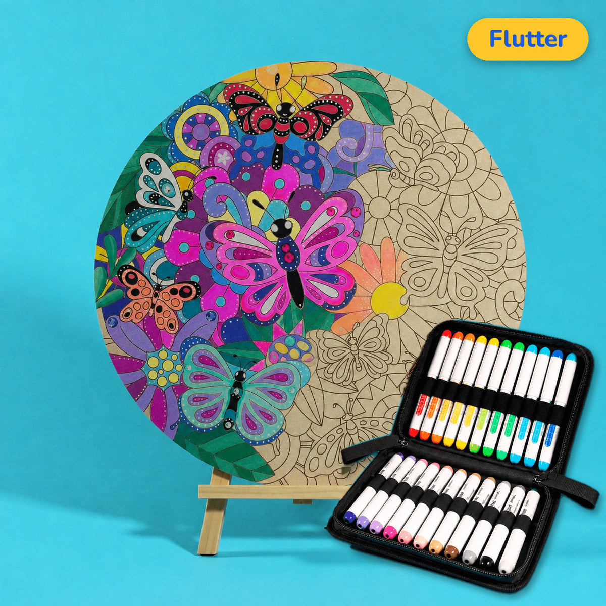 400mm Flutter engraved circle art board with butterflies, flowers and swirls, left half coloured pink, purple and teal, beside a case of 24 Nahuku markers
