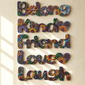 Multicolor decorative wall art spelling out 'Belong Kind Friend Love Laugh' in engraved floral-patterned letters, mounted on a beige wall with soft window-shadow lighting.