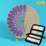 400mm Grace engraved circle art board with mandala of flowing hearts and petals, left half coloured purple, lilac and teal, beside a case of 24 Nahuku markers