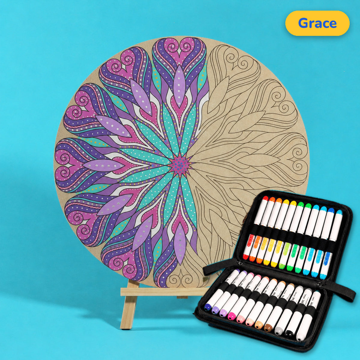 400mm Grace engraved circle art board with mandala of flowing hearts and petals, left half coloured purple, lilac and teal, beside a case of 24 Nahuku markers