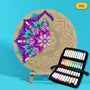 400mm Iris engraved circle art board with mandala of layered petals and drops, left side coloured purple, pink and teal, beside a case of 24 Nahuku markers