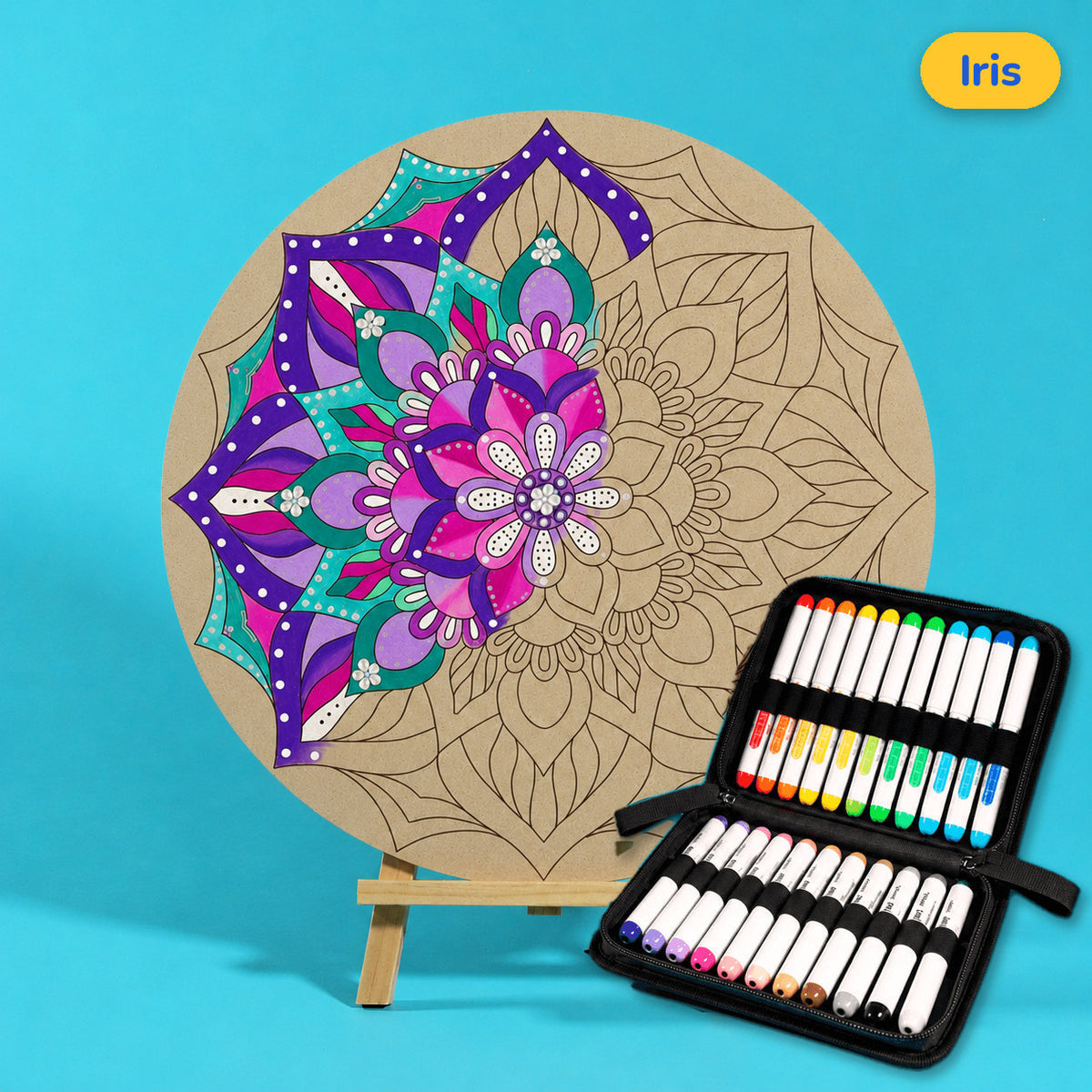 400mm Iris engraved circle art board with mandala of layered petals and drops, left side coloured purple, pink and teal, beside a case of 24 Nahuku markers