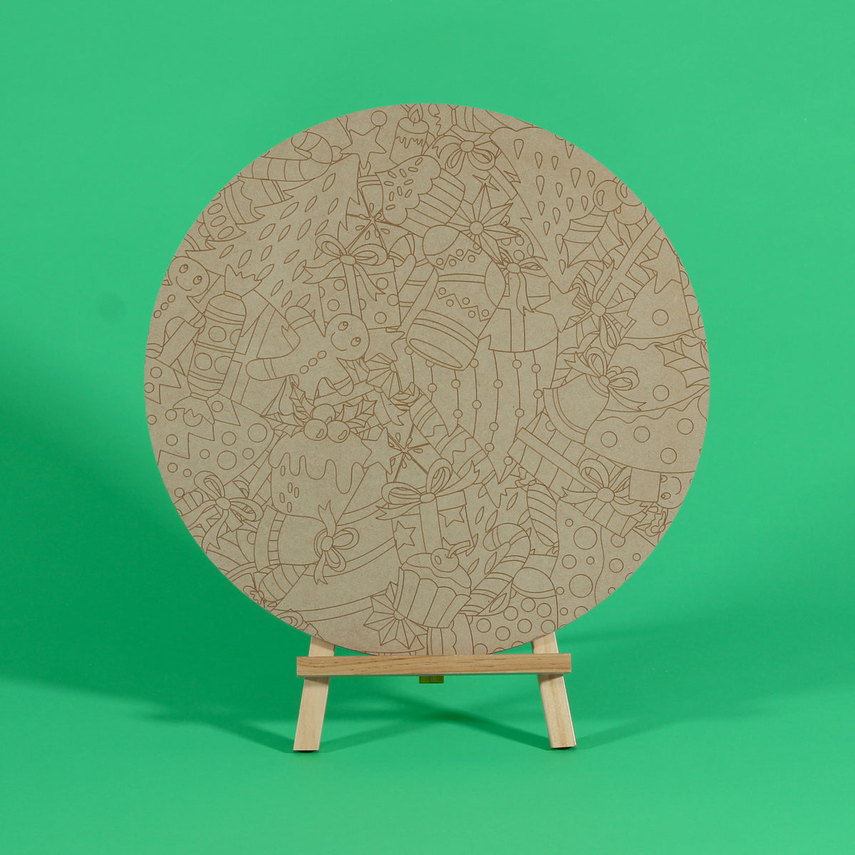 Uncoloured Jolly Tangle 400mm round MDF board on an easel, engraved with a tangle of gingerbread, presents, puddings and candy canes