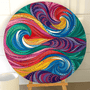 A large round canvas print featuring a vibrant, multicolored psychedelic swirl pattern, displayed on a wooden easel against a white paneled wall.