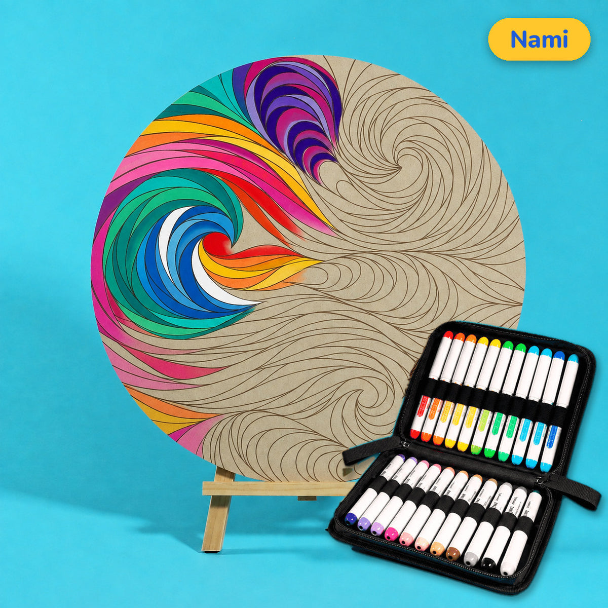 400mm Nami engraved circle art board with sweeping, curling wave lines, one wave coloured in rainbow stripes, beside a case of 24 Nahuku markers