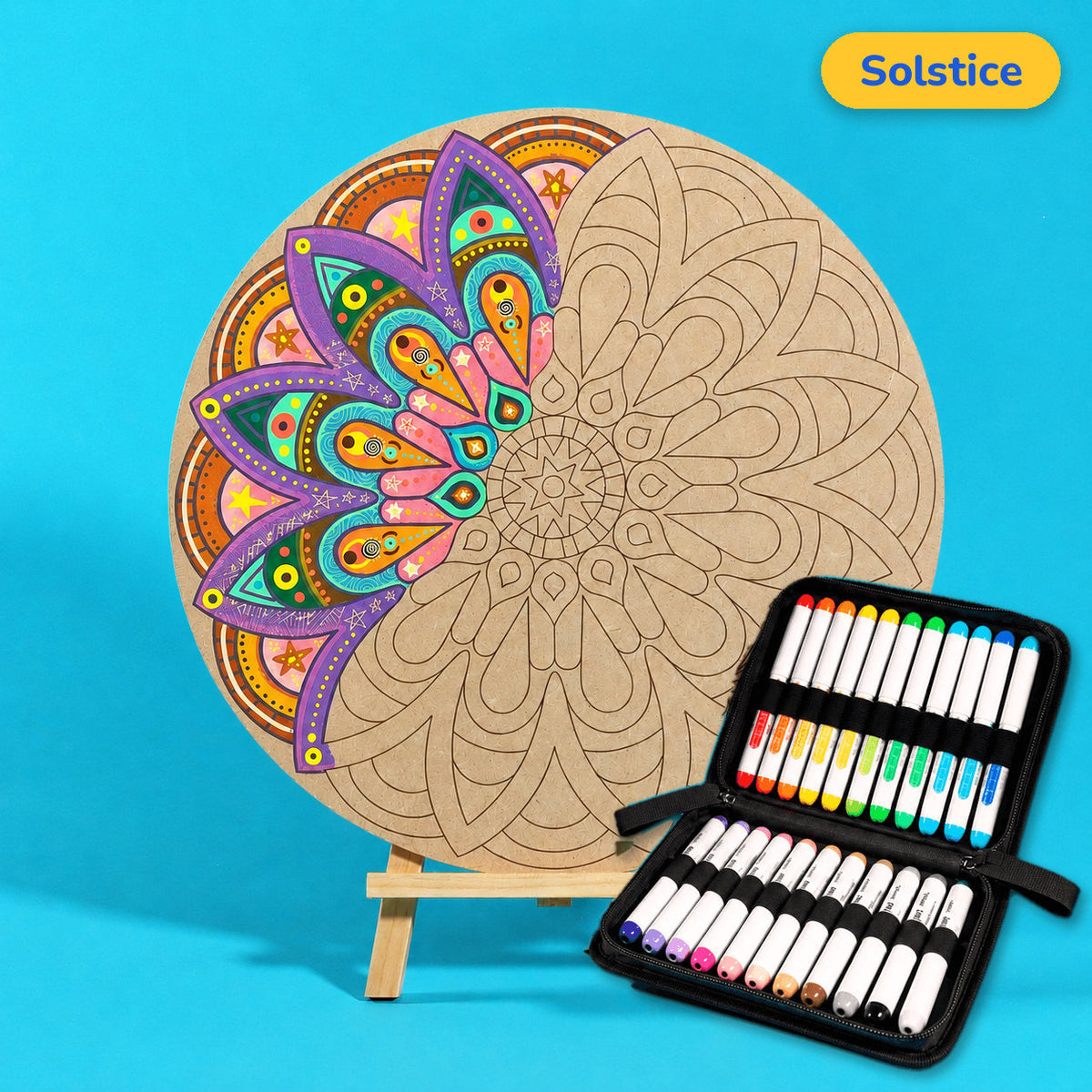 400mm Solstice engraved circle art board with mandala of sunburst petal layers, left side coloured purple, orange and teal, beside a case of 24 Nahuku markers
