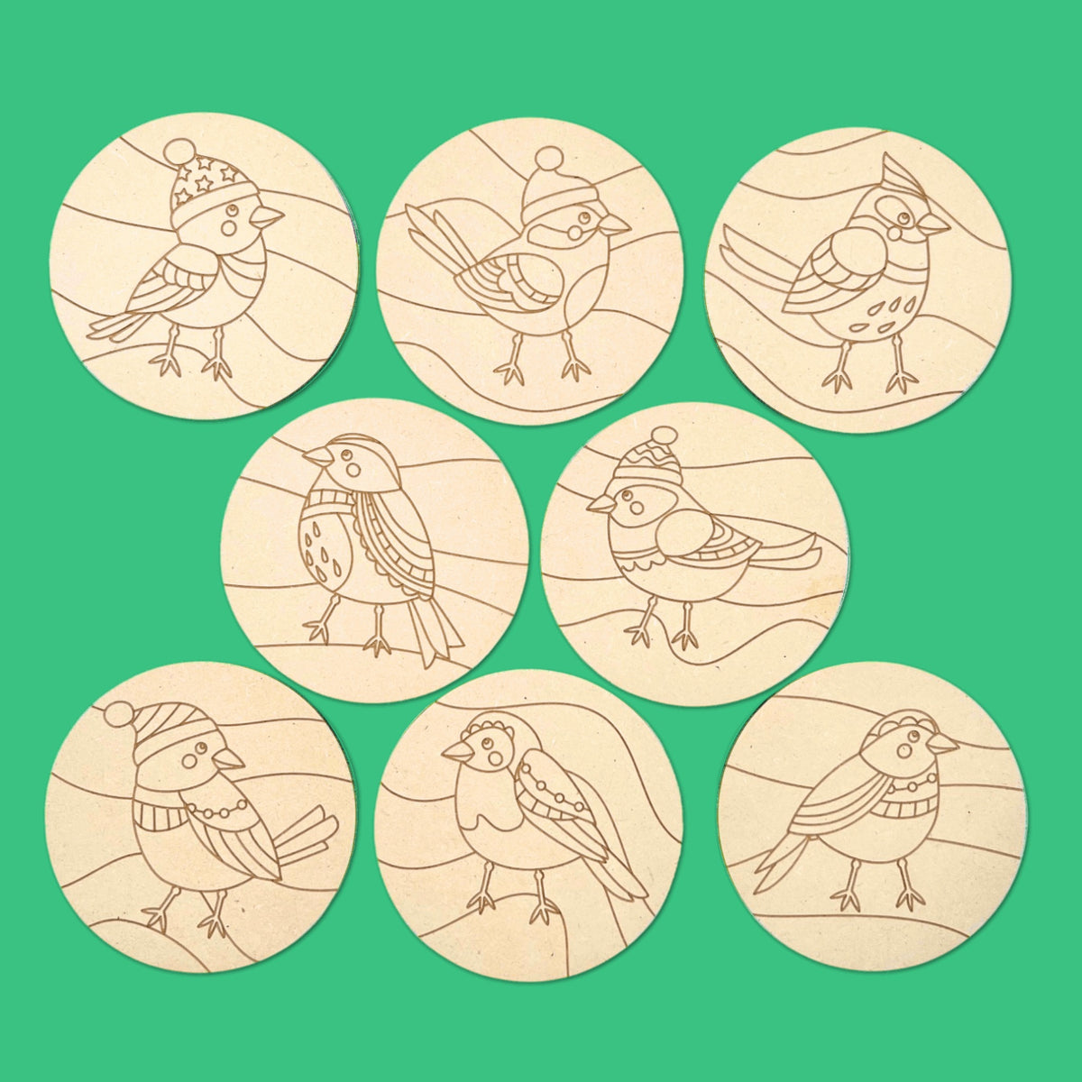 Songbird Christmas coasters laid out on green, a mindful Christmas craft kit for colouring and sealing