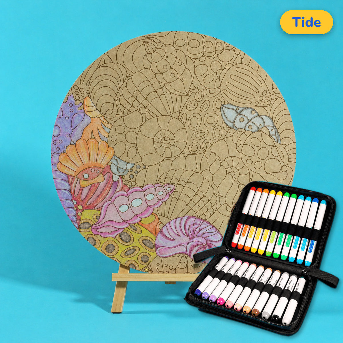 400mm Tide engraved circle art board with seashells and gentle curves, left side coloured pastel orange, pink and lilac, beside a case of 24 Nahuku markers