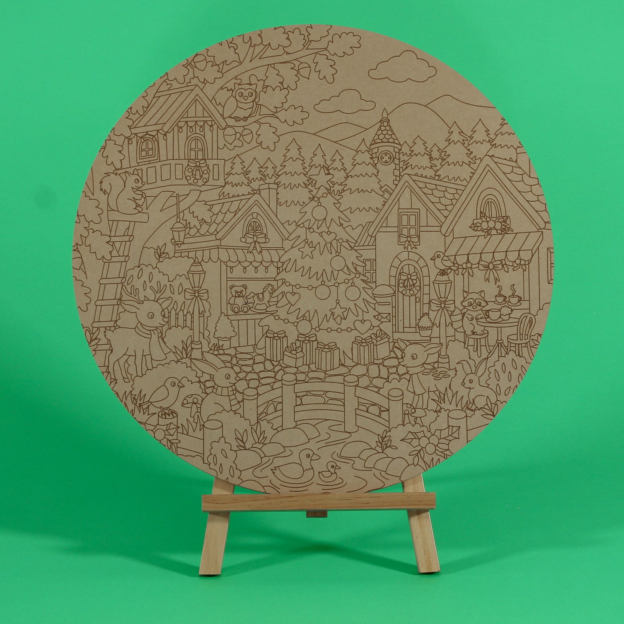 A Woodland Christmas engraved circle art board to colour on an easel, with deer, rabbits, ducks in a pond, owl, squirrel, raccoon, treehouse and Christmas tree