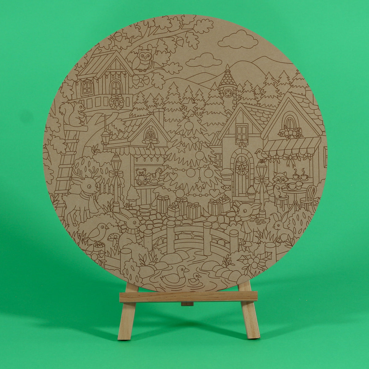 A Woodland Christmas engraved circle art board to colour on an easel, with deer, rabbits, ducks in a pond, owl, squirrel, raccoon, treehouse and Christmas tree